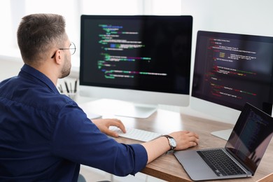 Young programmer working at desk in office, back view