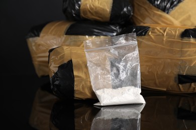 Photo of Smuggling and drug trafficking. Packages with narcotics on black mirror surface, closeup