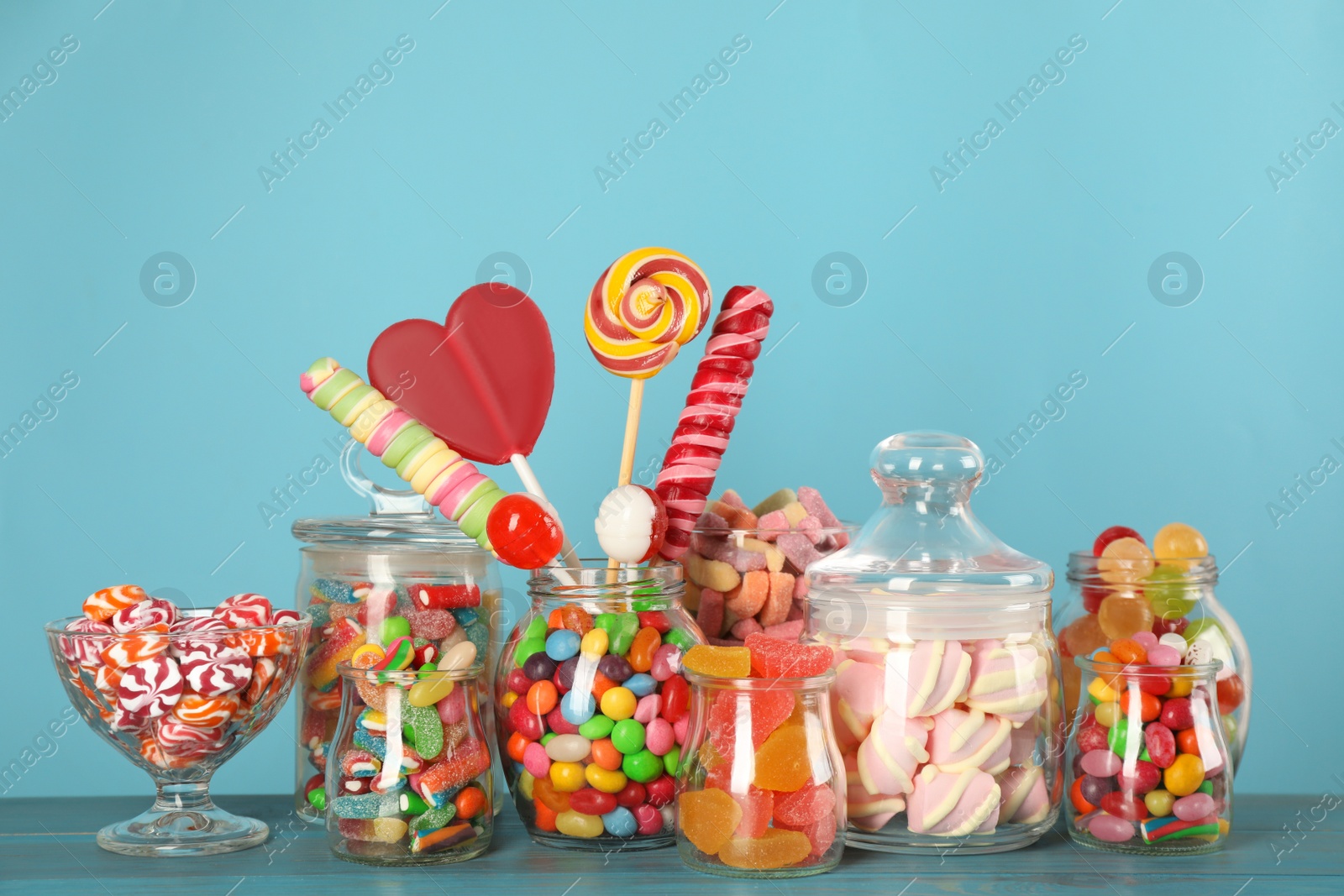 Photo of Jars with different delicious candies on turquoise wooden table