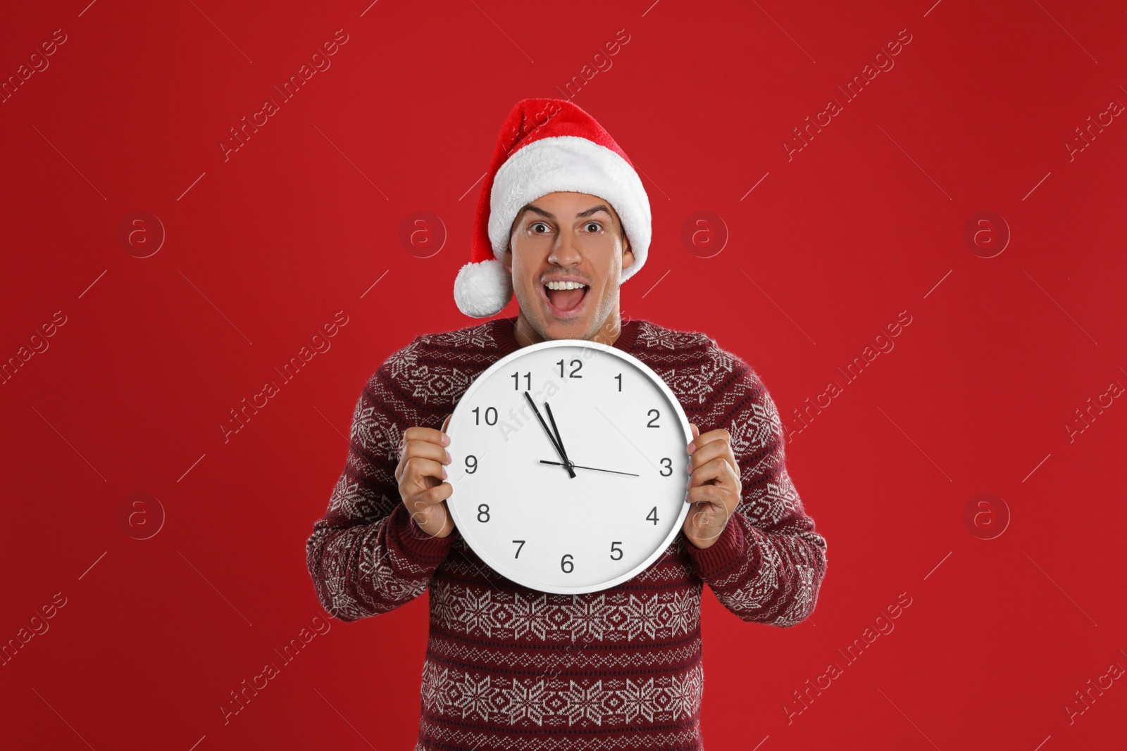 Photo of Man in Santa hat with clock on red background. New Year countdown