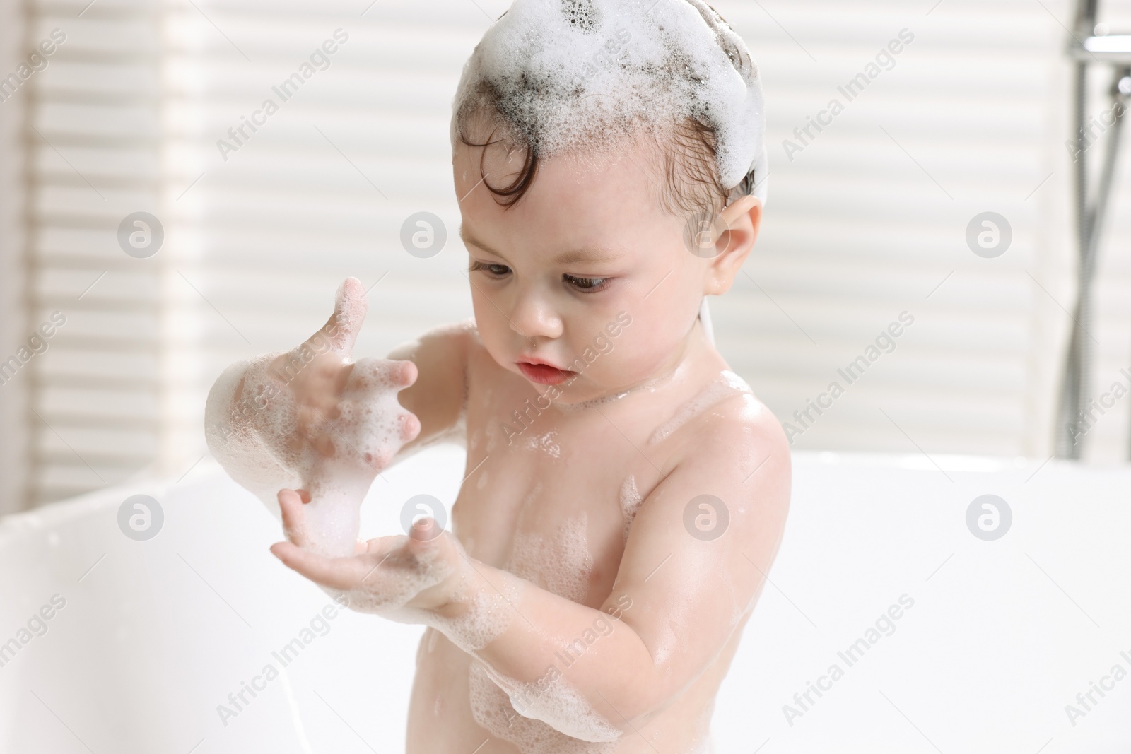 Photo of Cute little child bathing in tub at home