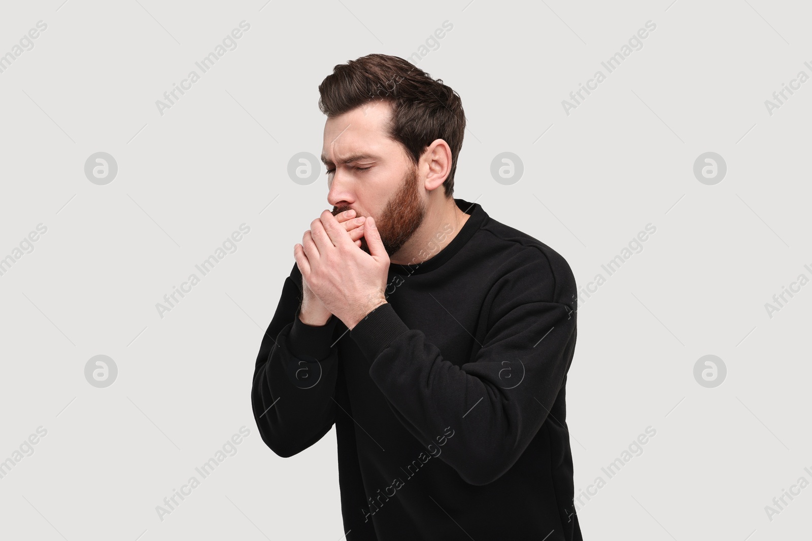 Photo of Sick man coughing on light grey background. Cold symptoms