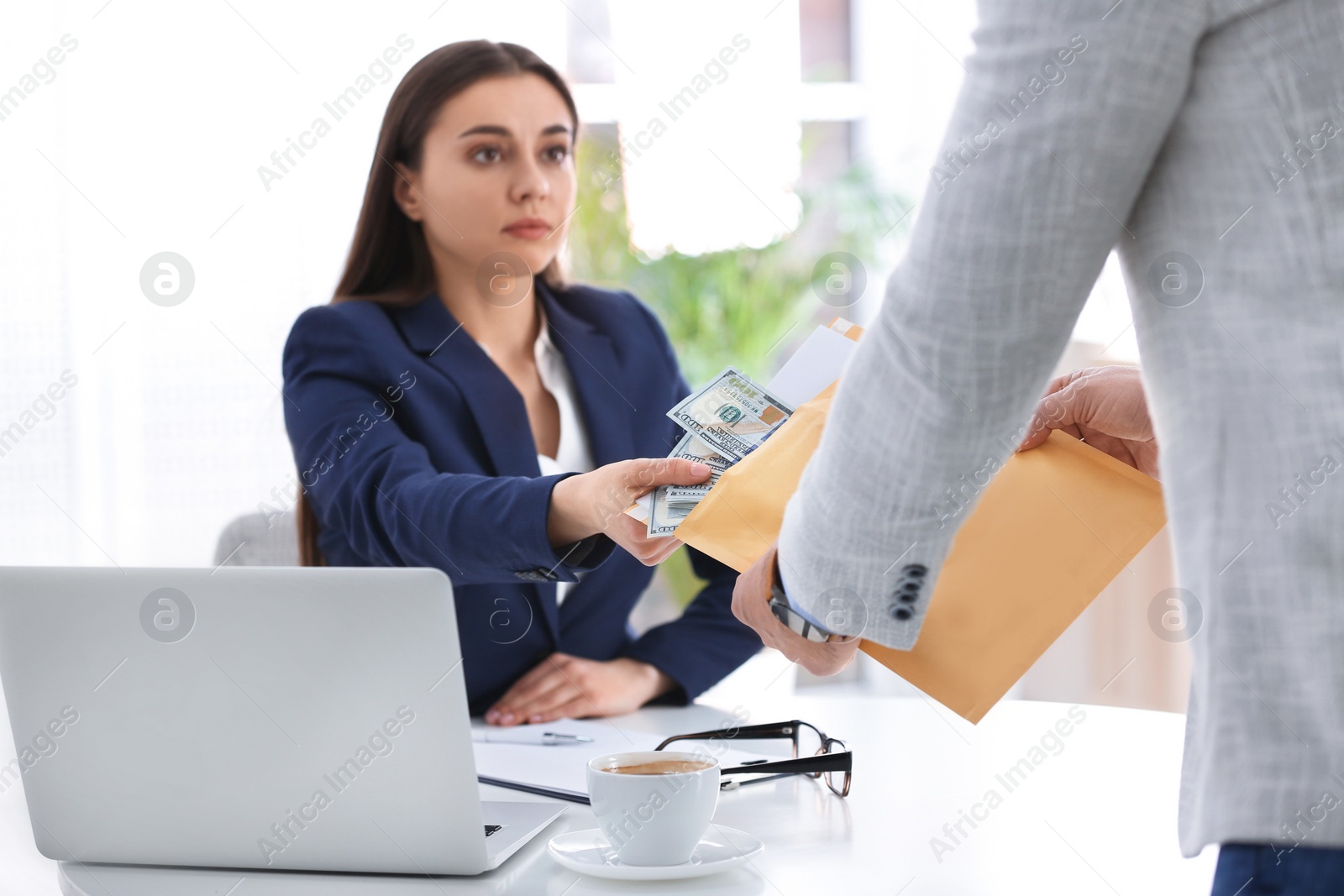 Photo of Man giving bribe to woman at table in office