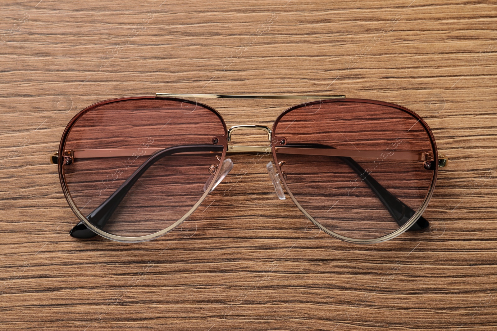 Photo of New stylish sunglasses on wooden table, top view