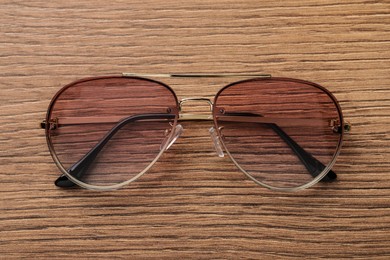 Photo of New stylish sunglasses on wooden table, top view