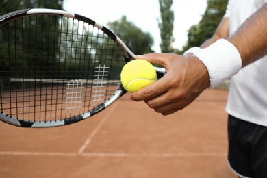 Sportsman preparing to serve tennis ball at court, closeup