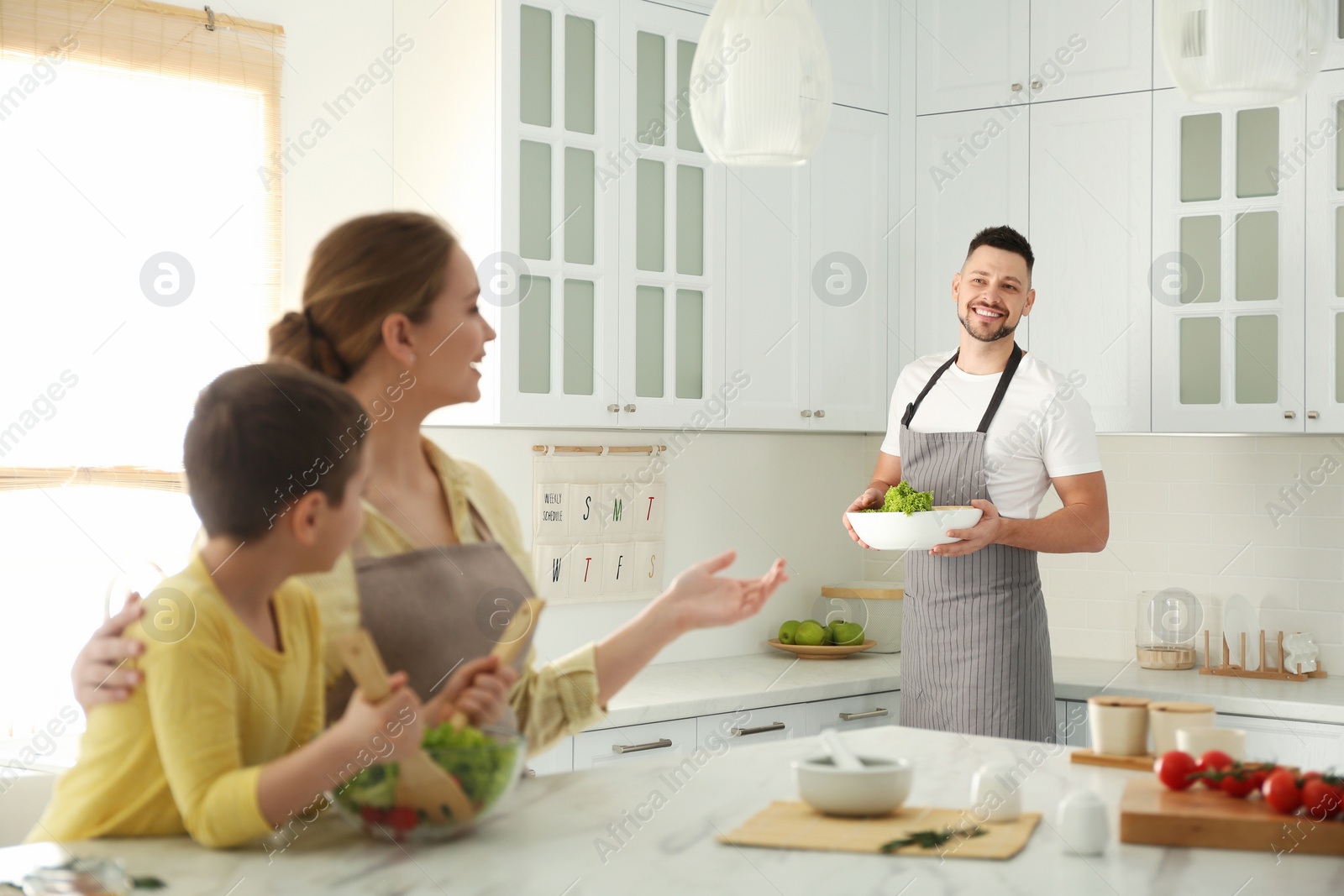 Photo of Happy family cooking salad together in kitchen