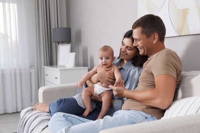 Photo of Happy family with their cute baby on sofa in living room