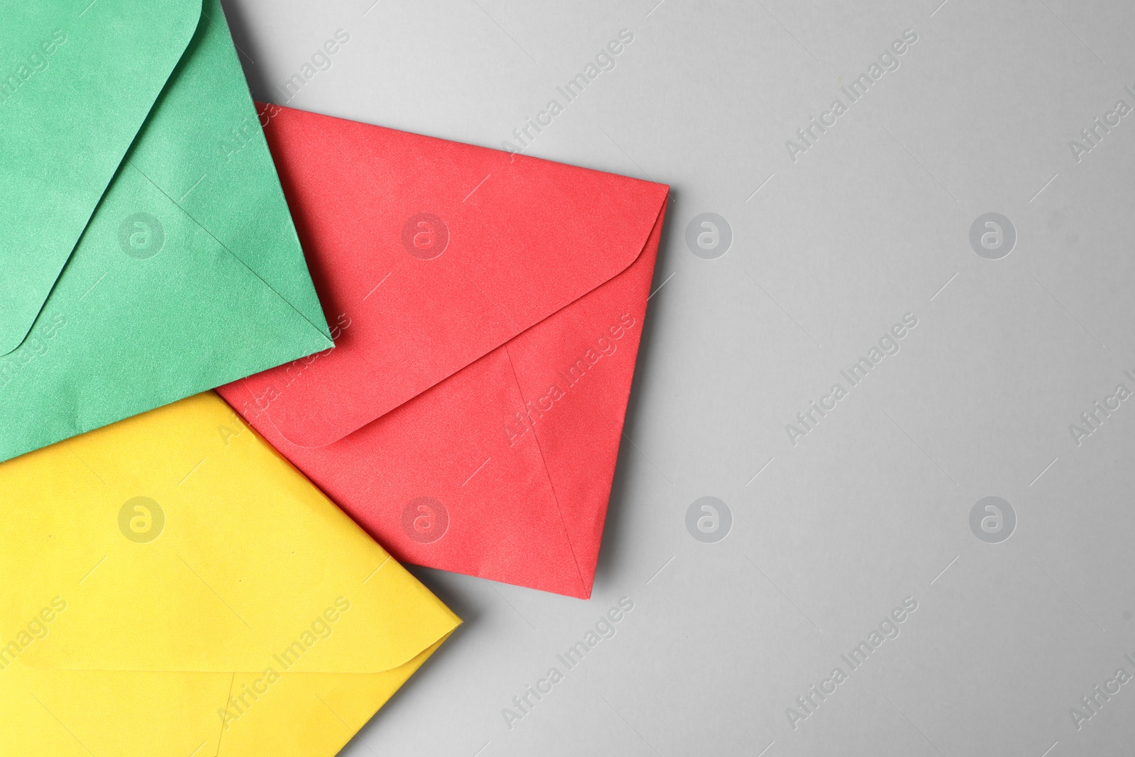 Photo of Colorful paper envelopes on light grey background, top view. Space for text