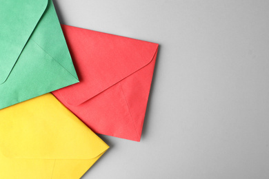 Colorful paper envelopes on light grey background, top view. Space for text