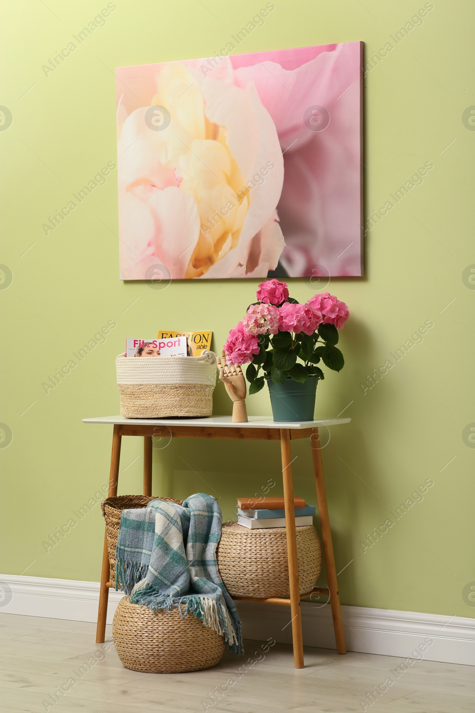 Photo of Console table with beautiful hortensia flower near light green wall in hallway. Interior design