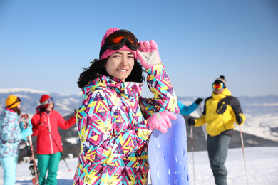 Photo of Young woman with snowboard at ski resort. Winter vacation