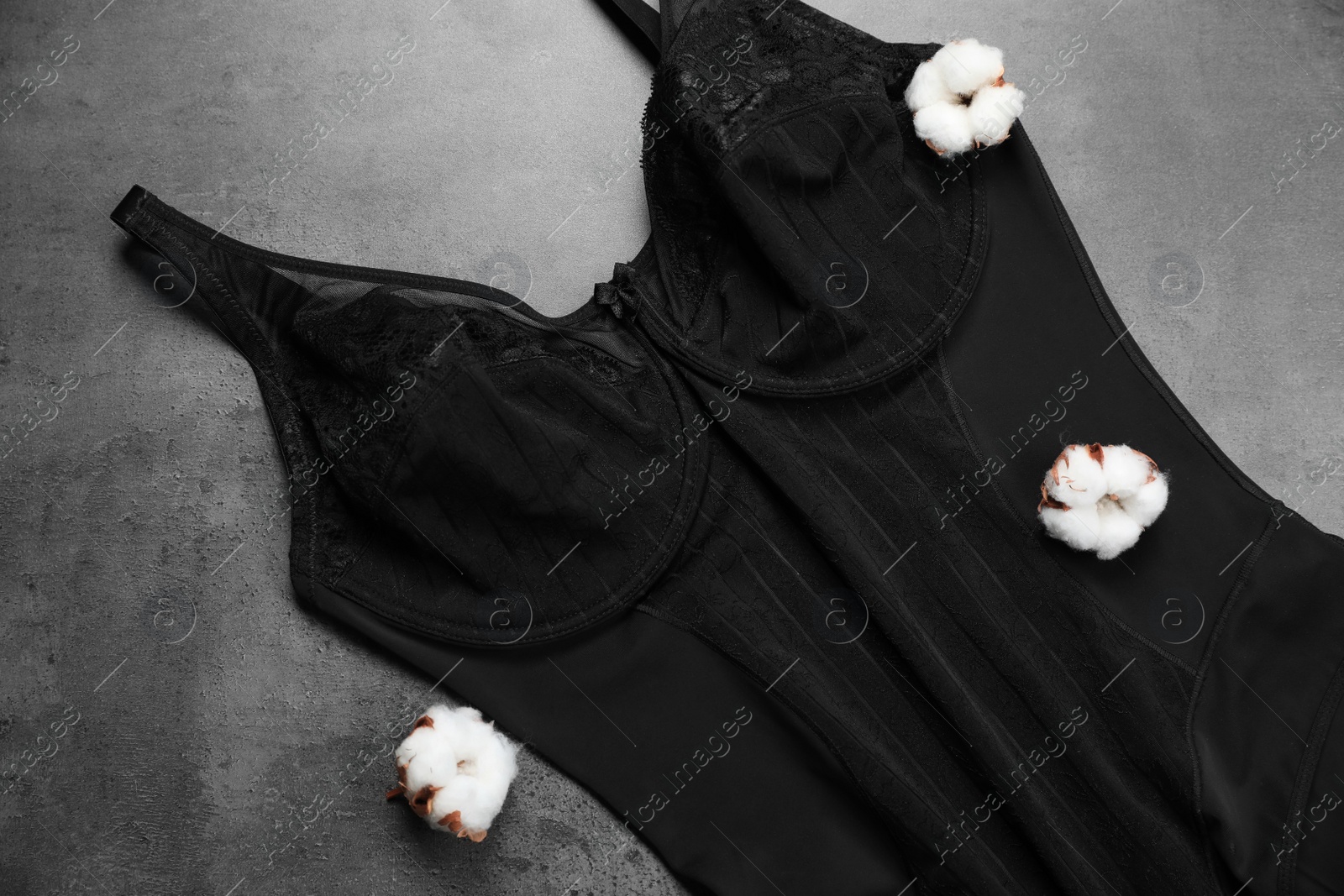 Photo of Elegant black plus size women's underwear and cotton flowers on grey background, flat lay