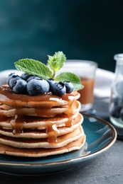 Photo of Delicious pancakes with fresh blueberries and syrup on grey table