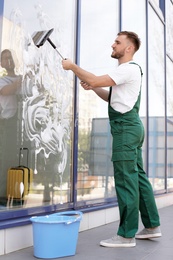 Photo of Male cleaner wiping window glass with squeegee from outside