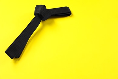 Photo of Black karate belt on yellow background, space for text