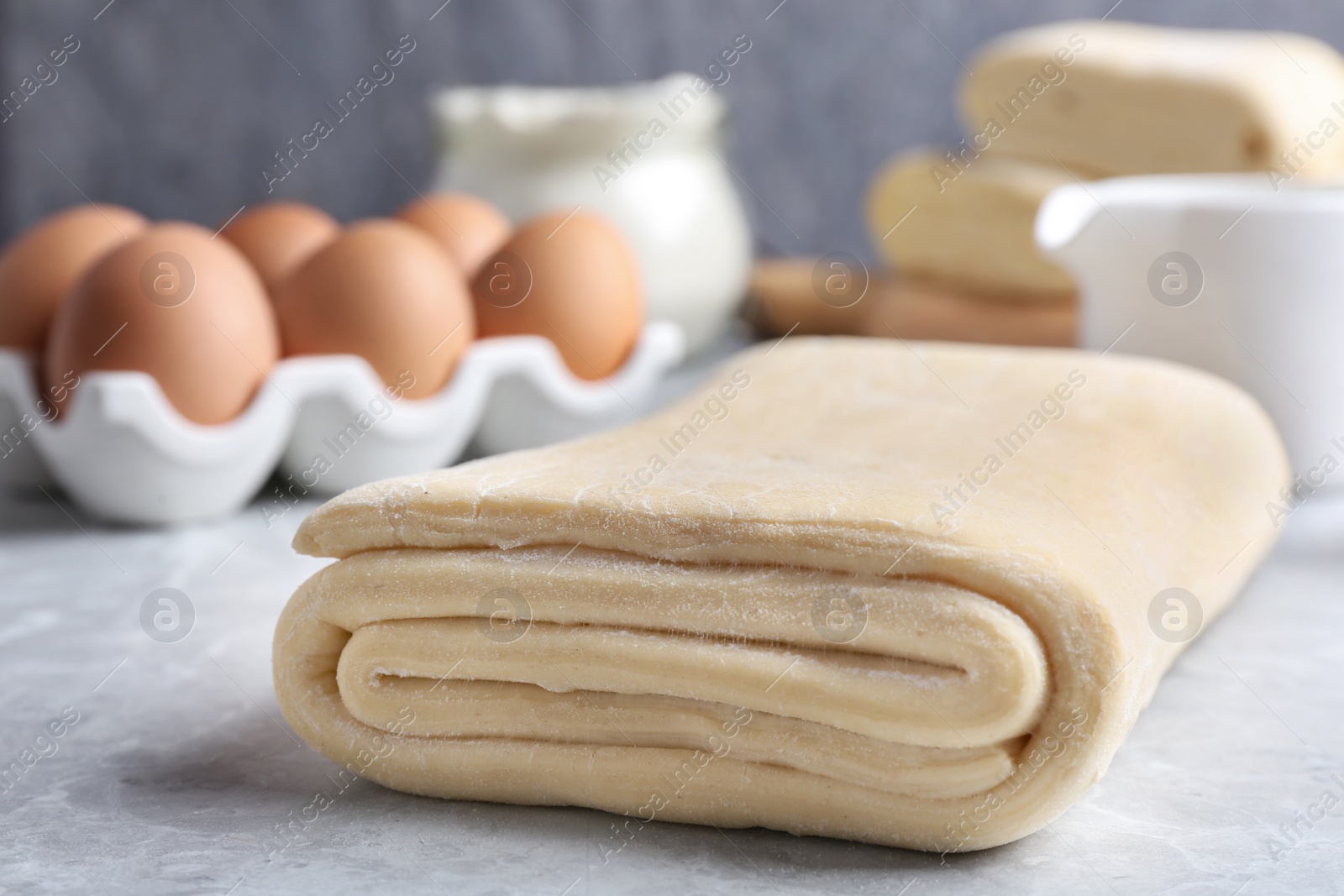 Photo of Raw puff pastry dough and ingredients on grey table