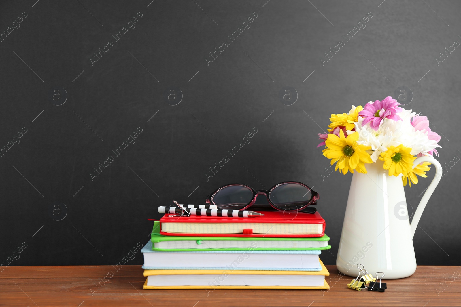 Photo of Bouquet of flowers and notebooks with eyeglasses on table. Teacher day celebration