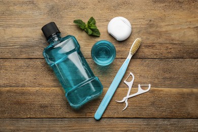Photo of Flat lay composition with mouthwash and other oral hygiene products on wooden table