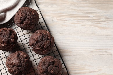 Photo of Delicious chocolate muffins on light wooden table, top view. Space for text