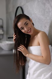 Photo of Smiling young woman after shower in bathroom