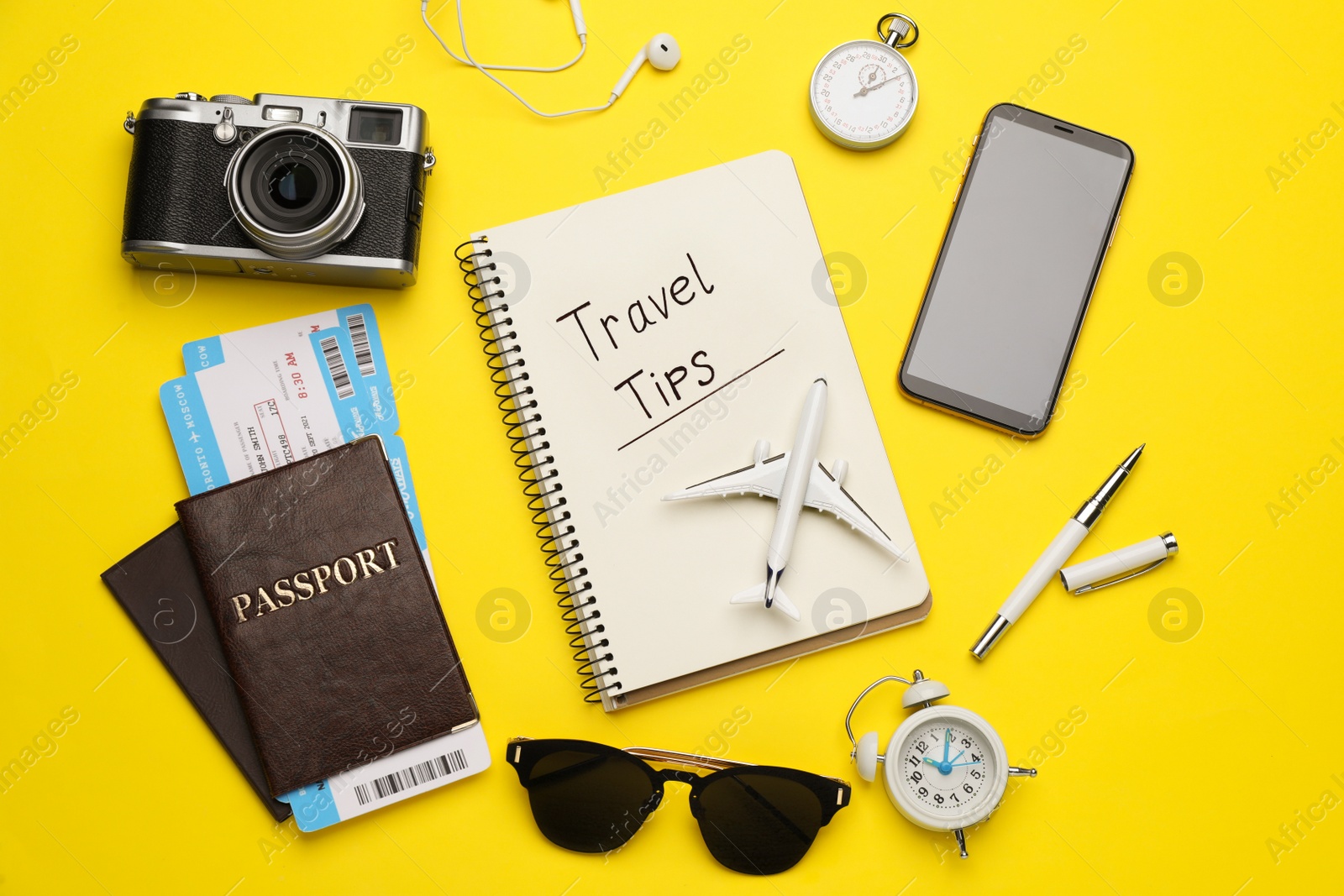 Photo of Flat lay composition with phrase Travel Tips written in notebook, passports, tickets and toy airplane on yellow background