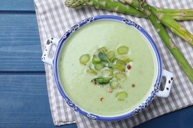 Delicious asparagus soup served on blue wooden table, flat lay