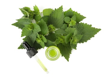 Photo of Glass bottle of nettle oil with dropper and leaves isolated on white, top view