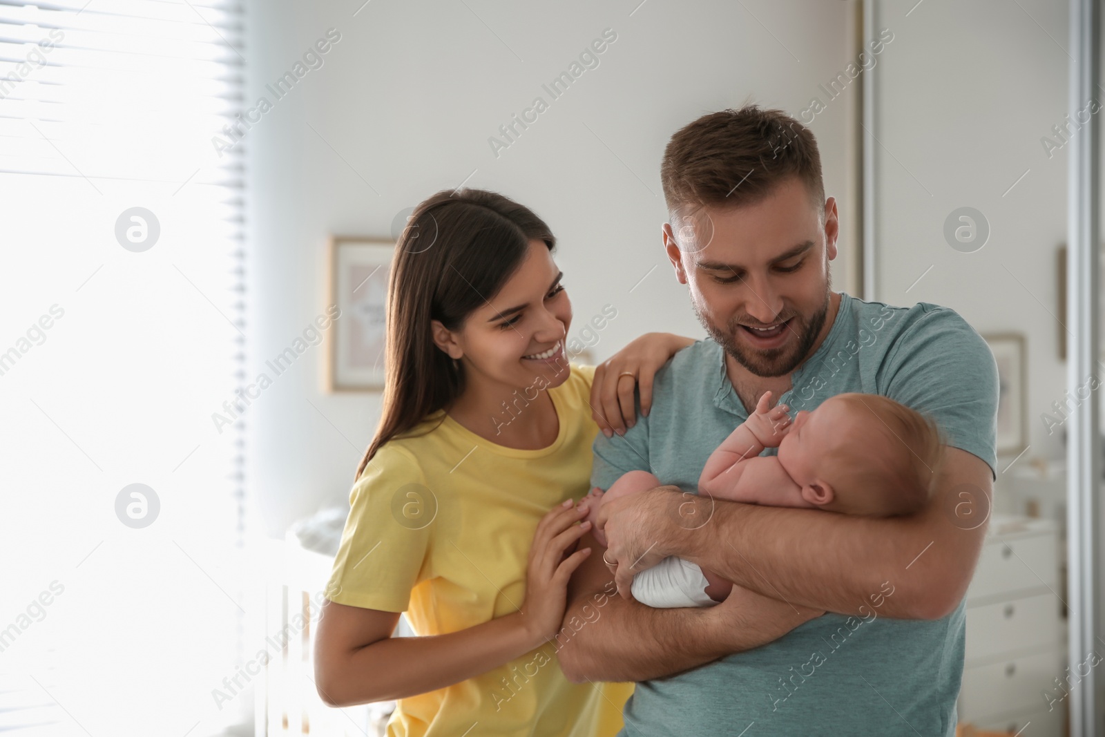 Photo of Happy couple with their newborn baby at home