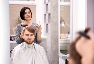 Professional female hairdresser working with client in salon