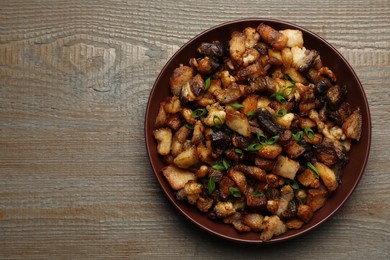 Tasty fried cracklings on wooden table, top view with space for text. Cooked pork lard