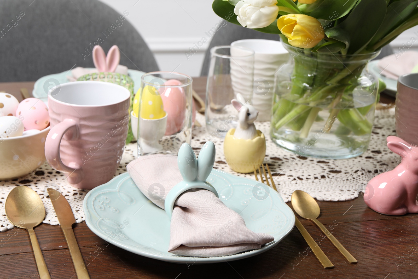 Photo of Festive table setting with napkin ring in shape of bunny ears. Easter celebration