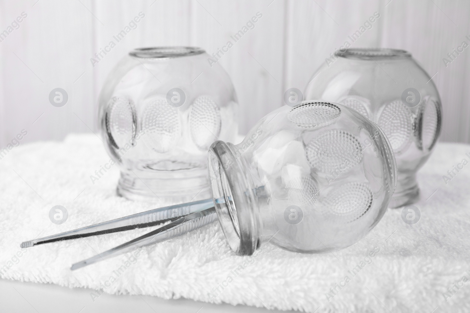 Photo of Glass cups and tweezers on white table, closeup. Cupping therapy