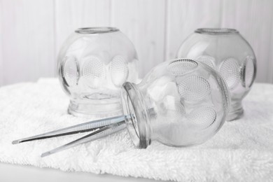 Glass cups and tweezers on white table, closeup. Cupping therapy