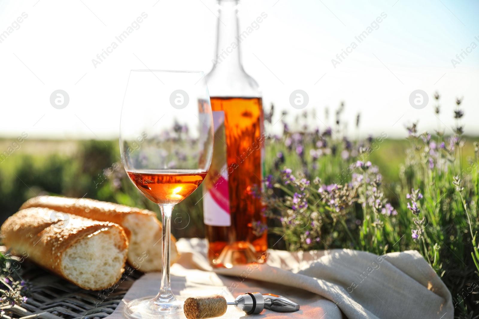 Photo of Composition with glass of wine on wicker table in lavender field. Space for text