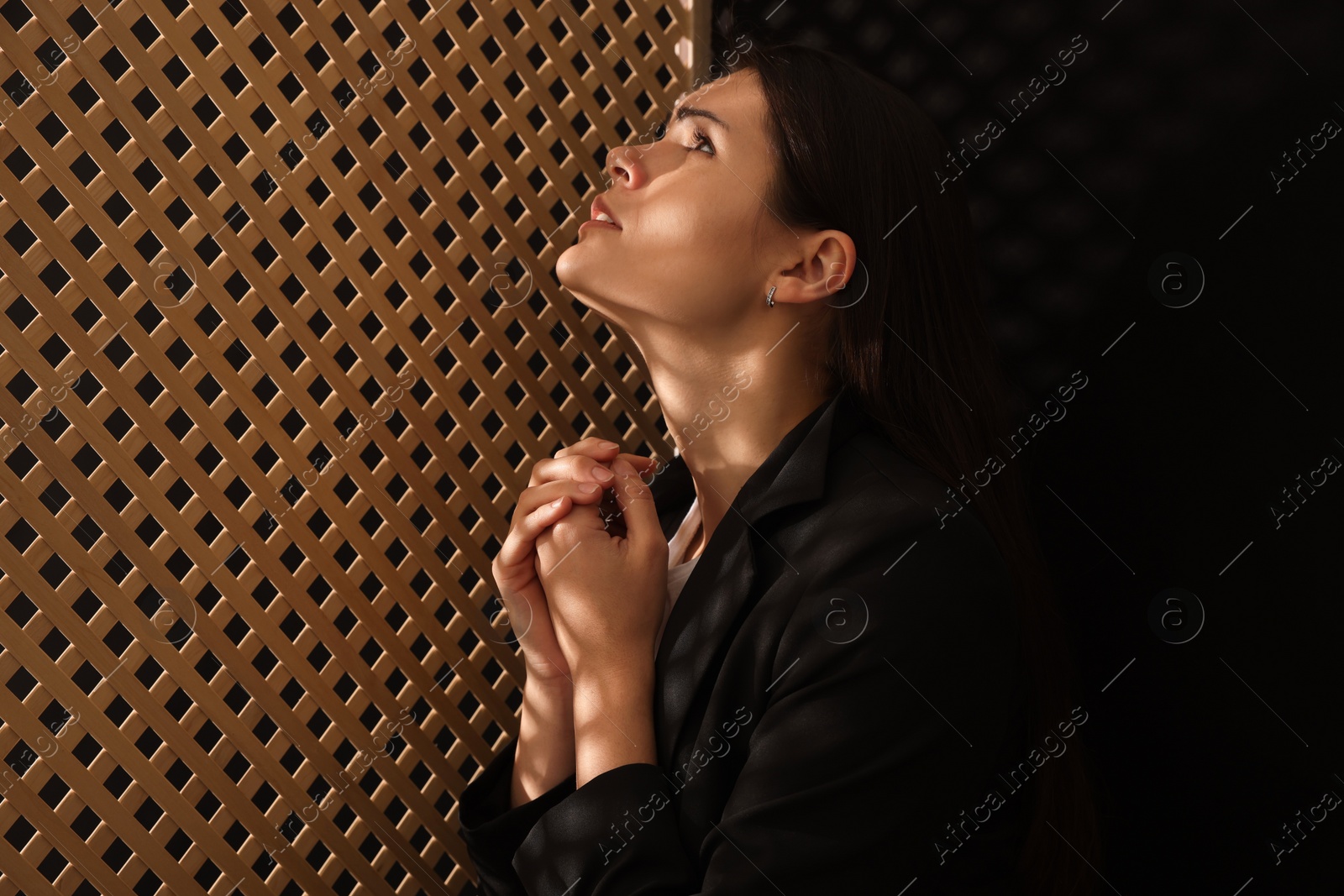 Photo of Woman praying to God during confession in booth