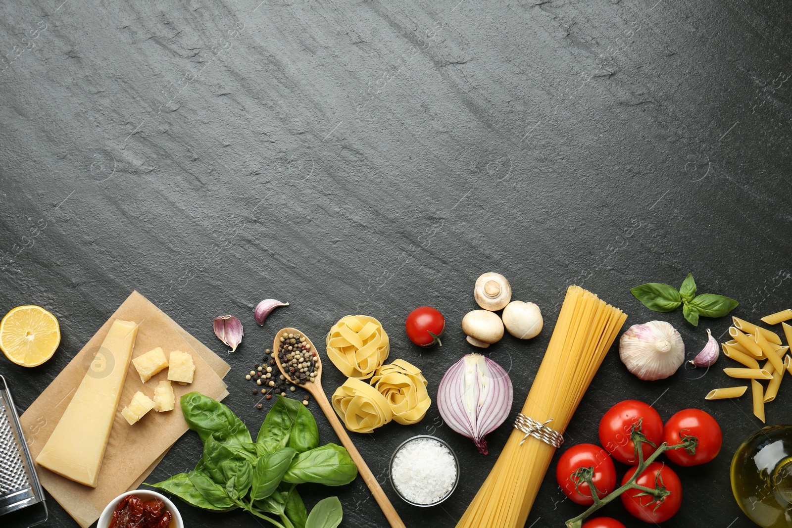 Photo of Different types of pasta, spices and products on dark textured table, flat lay. Space for text