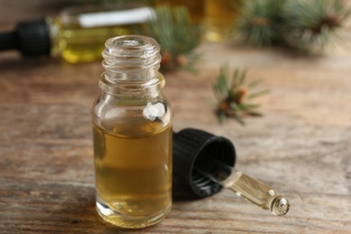 Photo of Bottle and pipette with conifer essential oil on wooden table