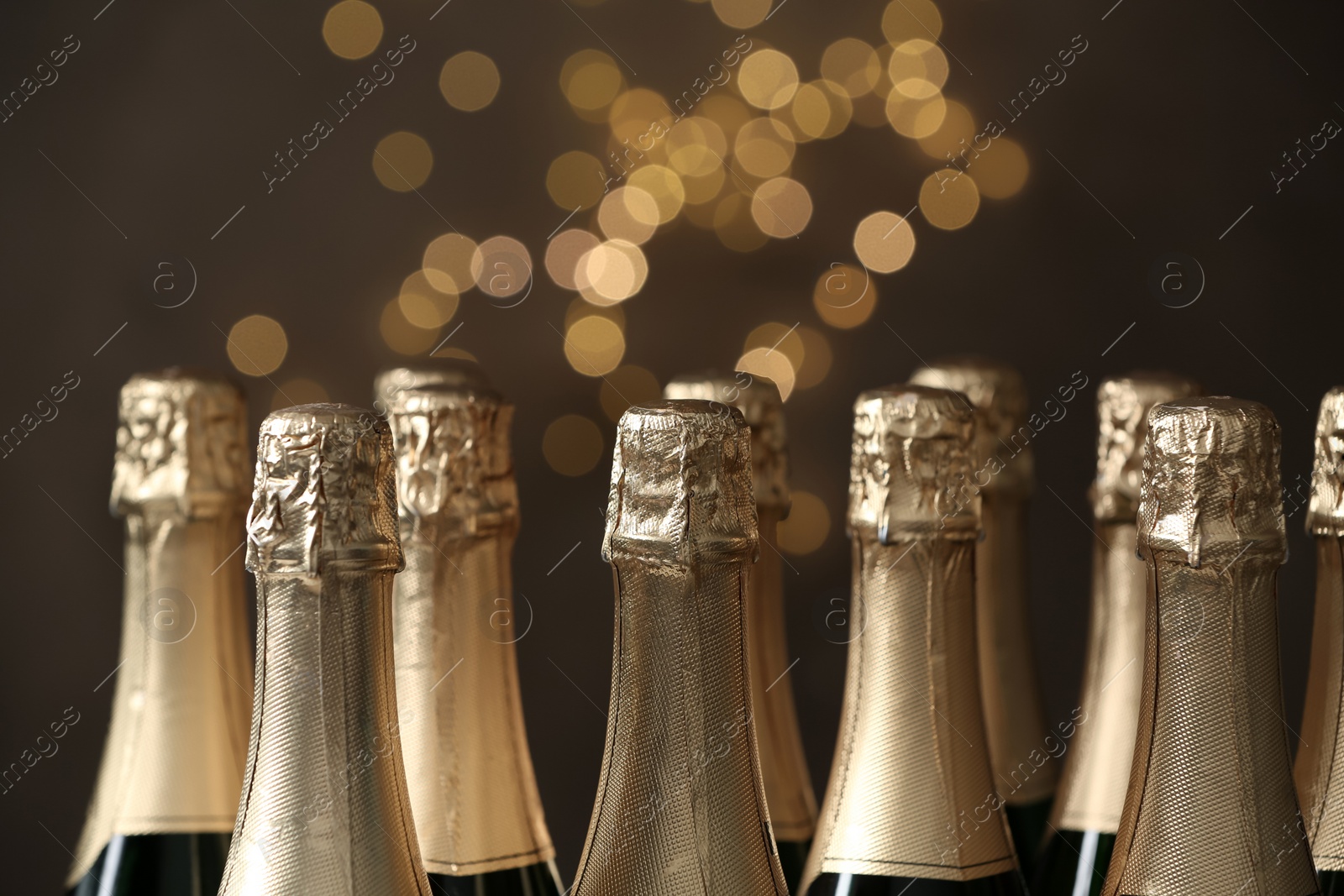 Photo of Many bottles of champagne on blurred background, closeup