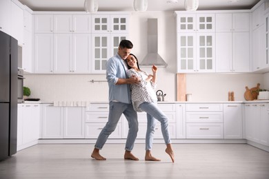 Photo of Happy couple dancing barefoot in kitchen. Floor heating system