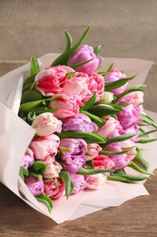 Photo of Bouquet of beautiful tulips on wooden table, closeup