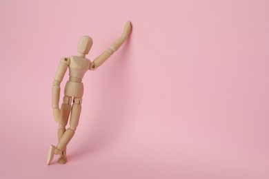 Photo of Wooden human model on pink background, space for text. Mini mannequin