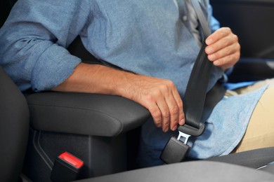 Photo of Man fastening safety seat belt in car, closeup
