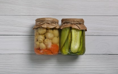 Photo of Jars with pickled vegetables on white wooden table, flat lay