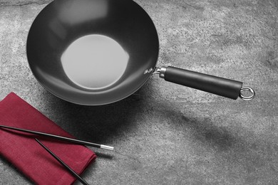 Empty iron wok and chopsticks on grey table