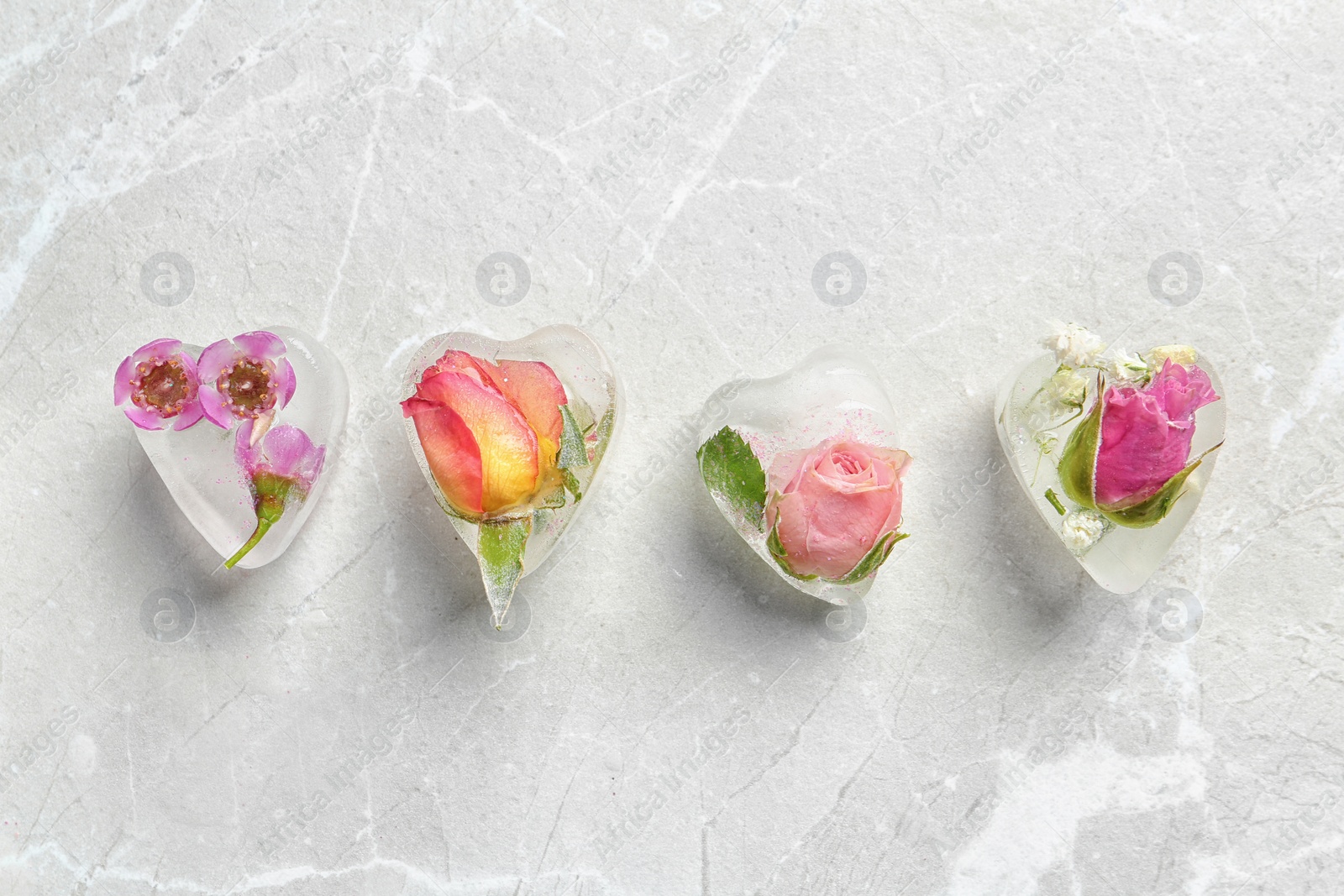 Photo of Heart shaped floral ice cubes on light background, top view