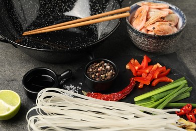 Photo of Different products and wok with chopsticks on dark table, closeup