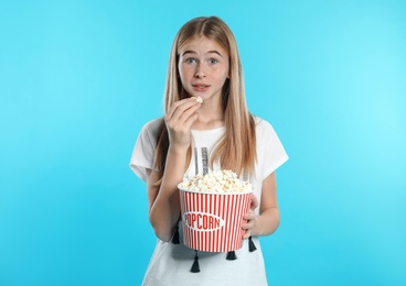 Photo of Emotional teenage girl with popcorn during cinema show on color background