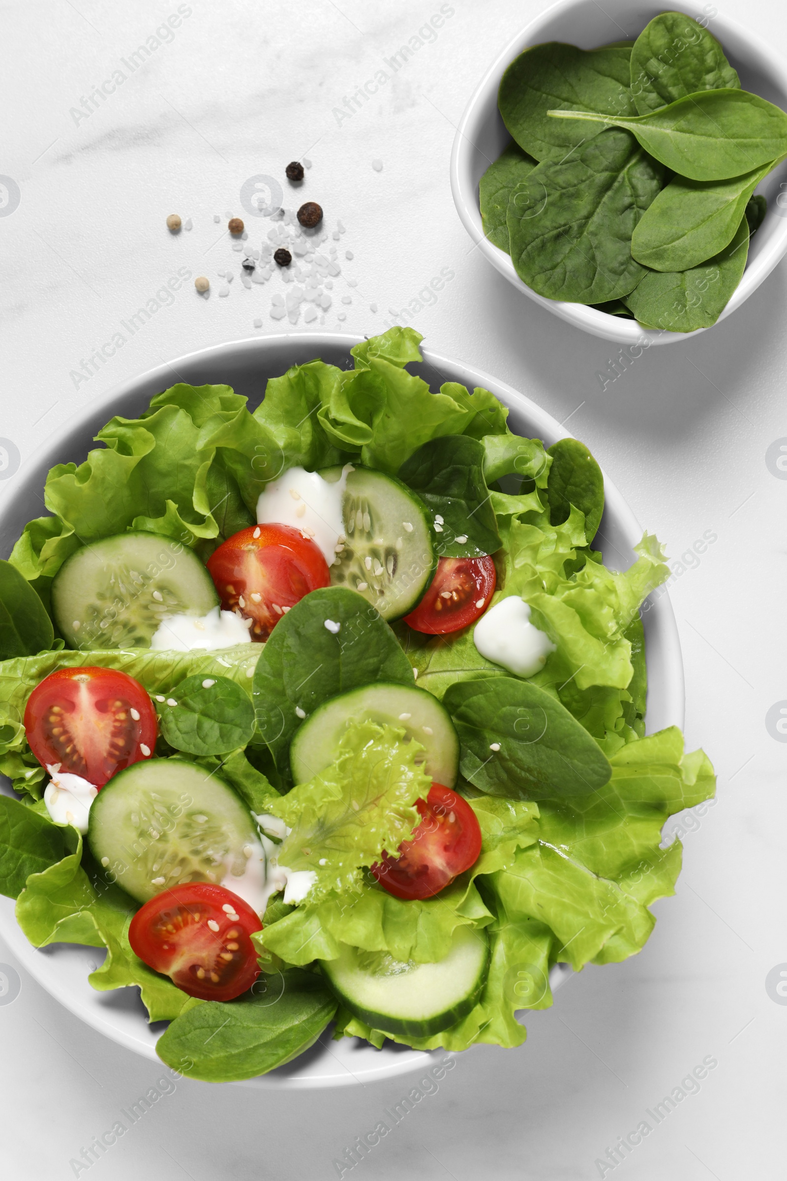 Photo of Delicious salad in bowl on white marble table, flat lay
