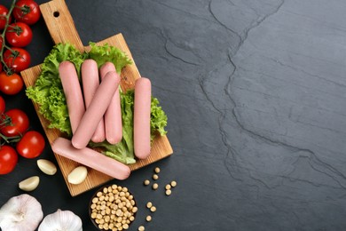 Photo of Fresh raw vegetarian sausages and vegetables on black table, flat lay. Space for text